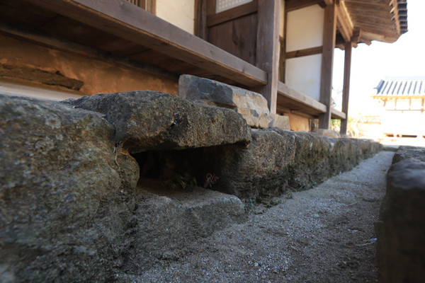 돌을 쌓아 올린 기단부에 네모진 구멍 하나를 비워 놓았을 뿐인 굴뚝. 이진래 고택.
