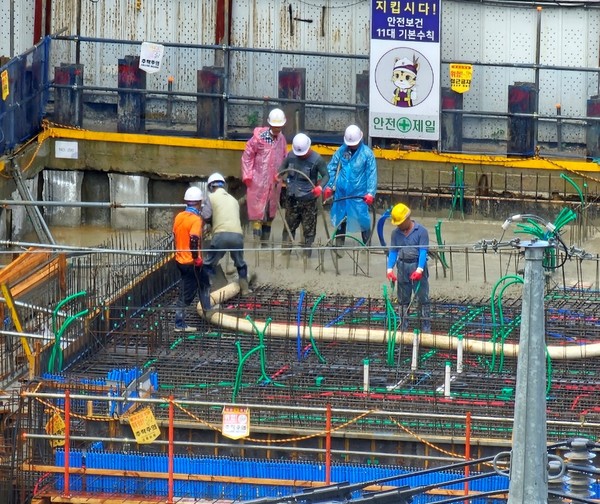 비가 내린 지난 17일 오전 9시경 화정동 인근 신축 아파트 건설 현장에서 콘크리트 타설 작업을 하고 있는 작업자들. 제보자 제공.