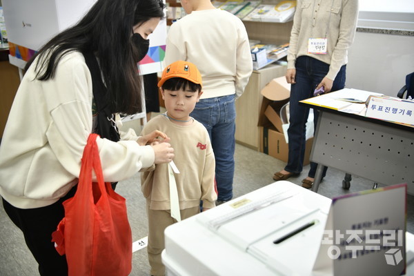제22대 국회의원 선거 투표일인 10일 오전 광주 서구 화정4동행정복지센터에서 유권자가 아들과 함께 투표용지를 넣고 있다.