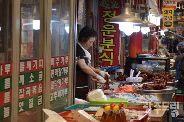 무더운 여름날, 거창시장의 한 상인이 음식을 조리하고 있다.