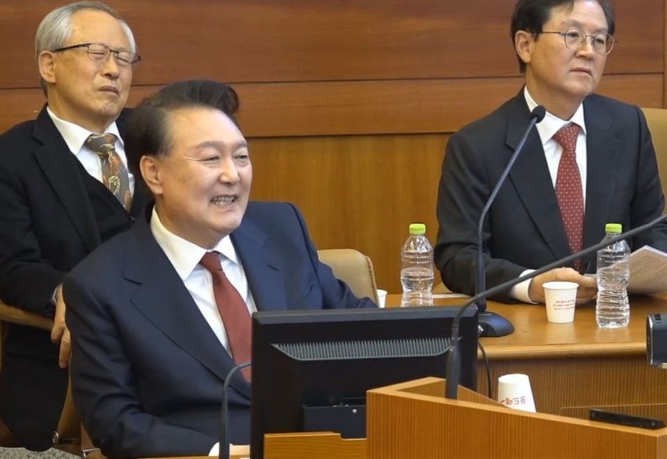 내란 우두머리 혐의로 구속된 윤석열 대통령이 1월 23일 오후 서울 종로구 헌법재판소에서 열린 탄핵심판 4차 변론에 출석, 김용현 전 국방장관을 상대로 증인신문하며 웃고 있다. 헌법재판소 화면 캡춰