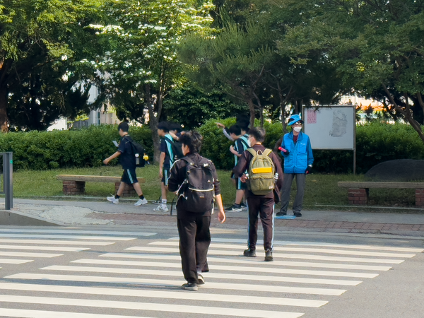 등굣길 횡단보도 앞, 파란 조끼를 입은 ‘우리학교보안관’이 학생들의 안전한 보행을 돕고 있다.