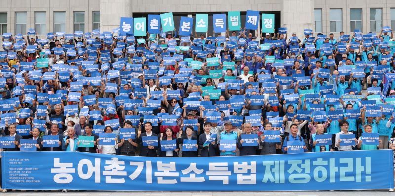 지난 9월 12일 서울 여의도 국회 본청 앞 계단에서 열린 농어촌기본소득법 제정 촉구 기자회견에서 참가자들이 손피켓을 들고 구호를 외치고 있다. 뉴시스